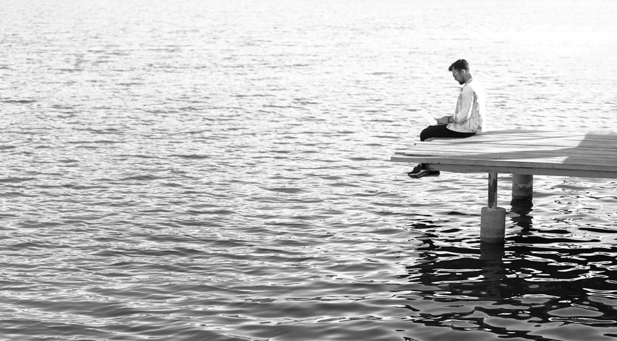 Man sittande på en brygga med en dator