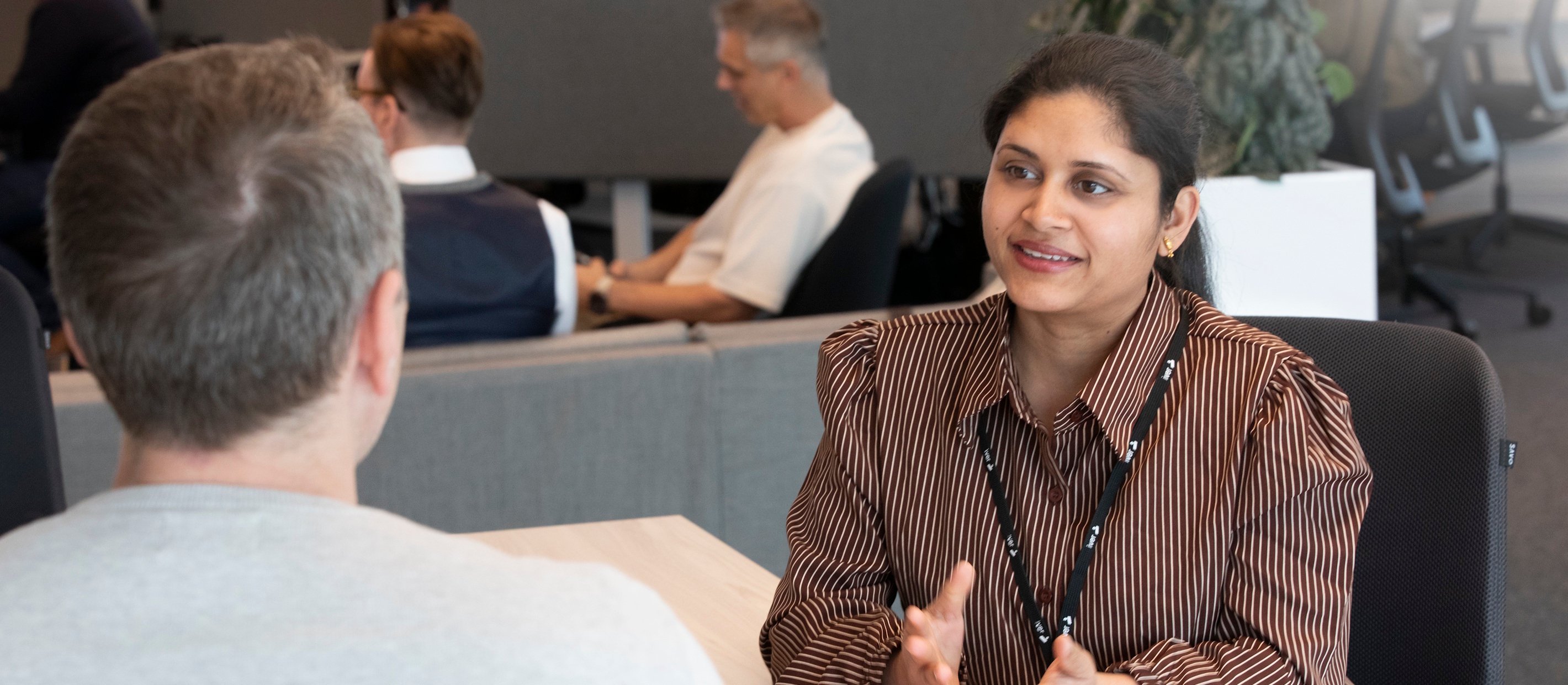 En kvinna och en man som pratar med varandra i ett kontorslandskap