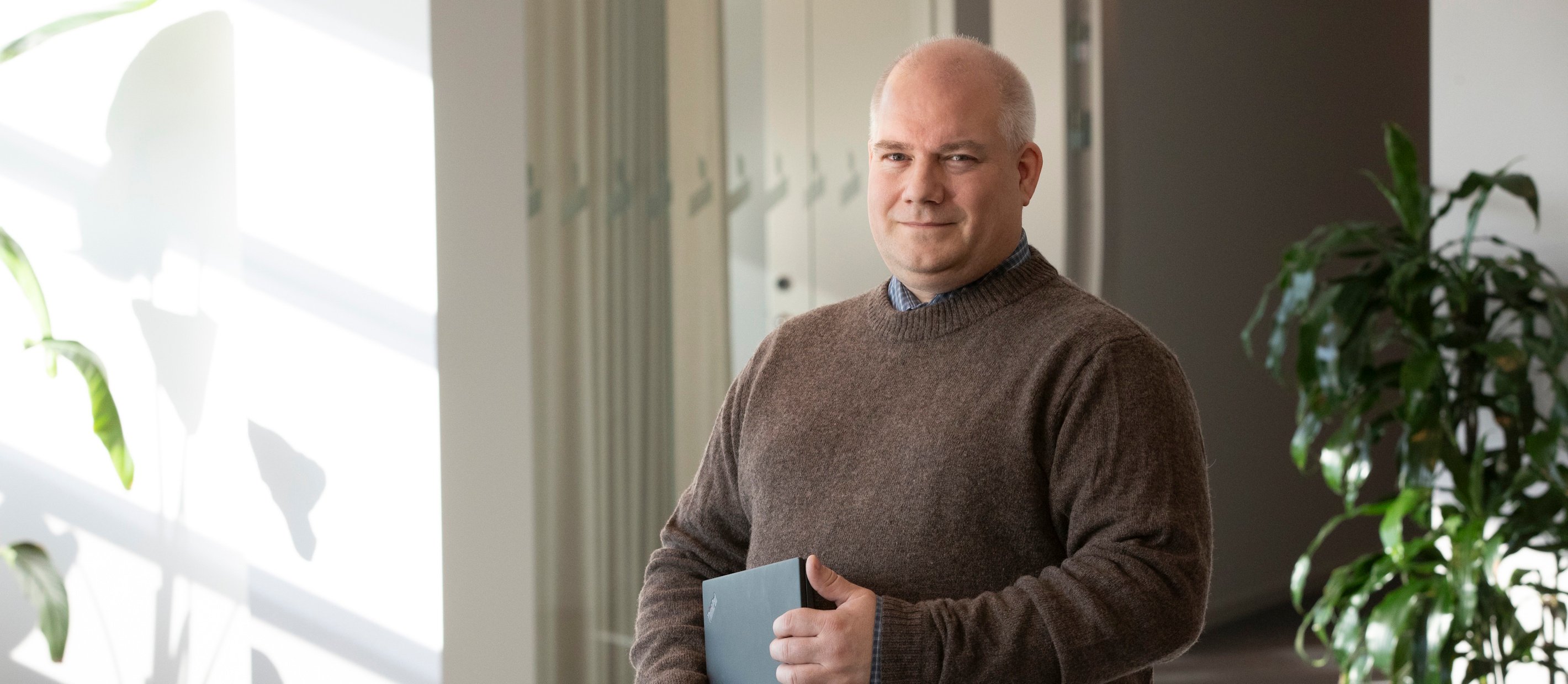 En man som står på kontoret med en dator under armen