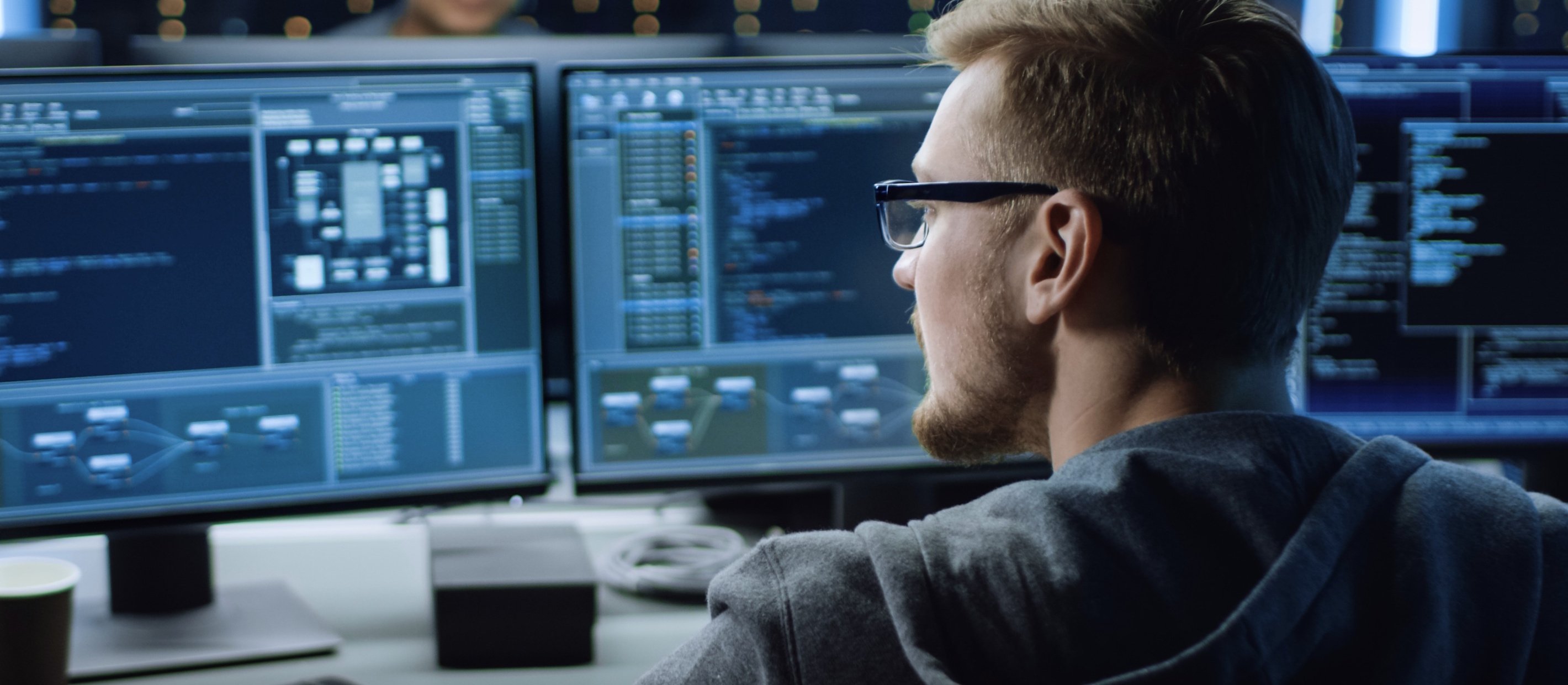 Säkerhetskonsult som sitter framför flera datorskärmar