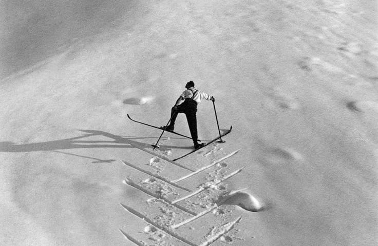 Mann som går oppover en skibakke i fiskebein