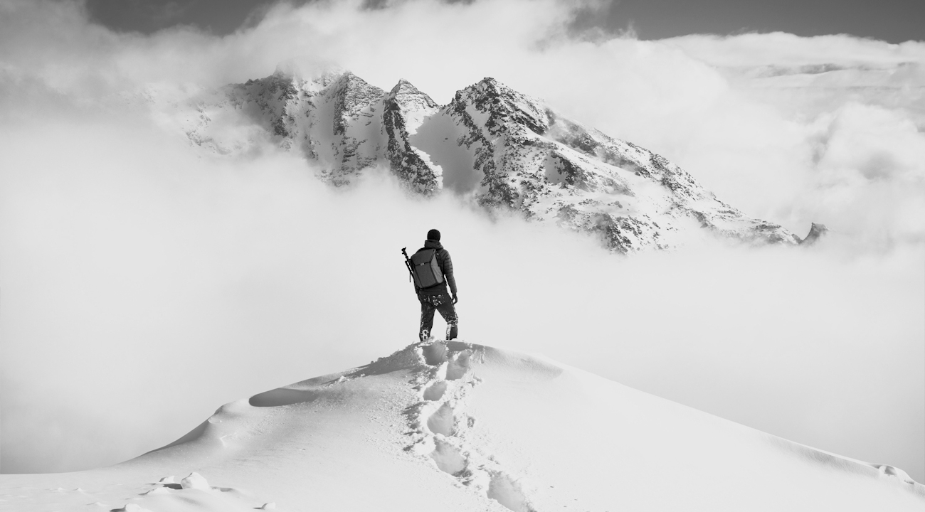 En man som står på ett snötäckt berg och blickar ut