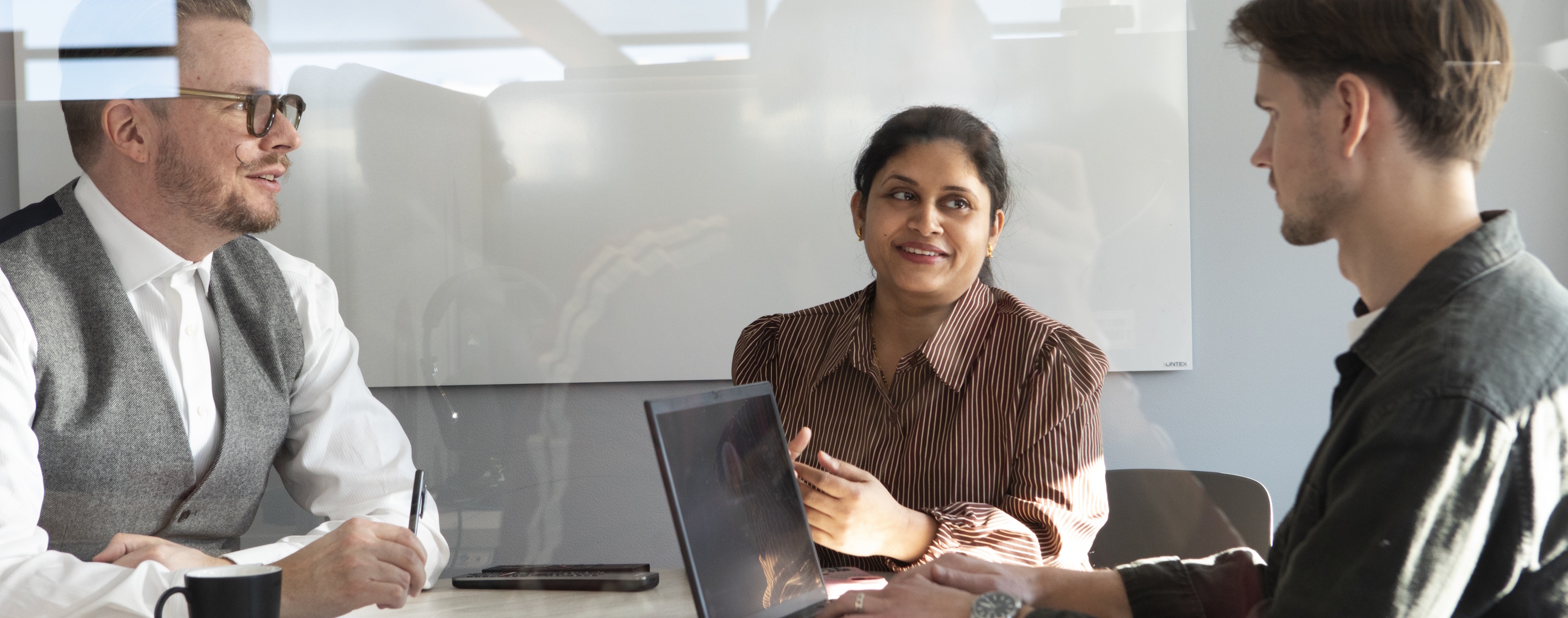 Tre kollegor som sitter i ett mötesrum med en dator