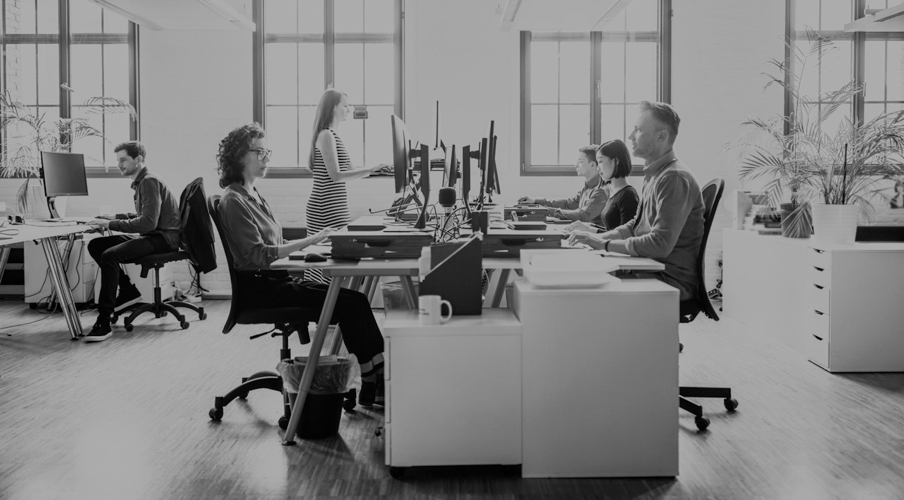 Moderna öppna kontorslandskap där människor sitter och arbetar med sina datorer